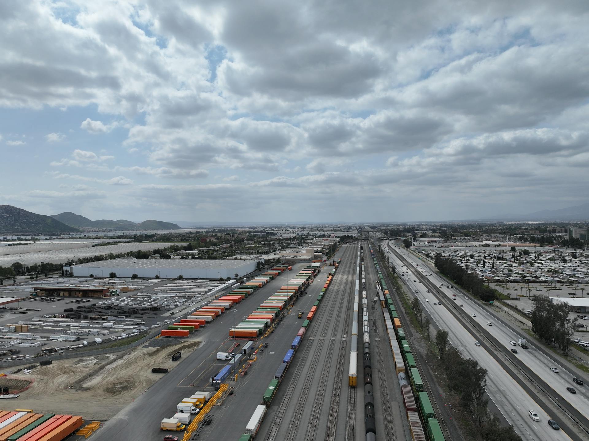 Aerial shot of a busy rail yard and logistics hub in California showcasing freight trains and transportation infrastructure.