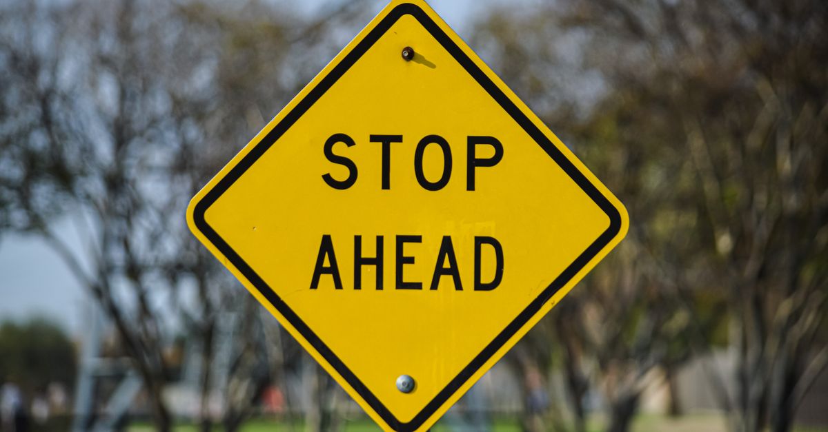 Vibrant yellow stop ahead sign in an outdoor park setting in Dallas, Texas.