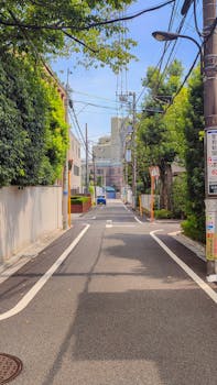 A peaceful urban street scene in Tokyo, Japan, showing residential buildings and trees.