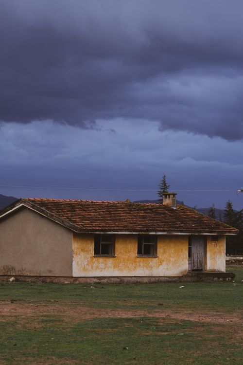 Free A solitary rural house under a dramatic stormy sky, highlighting rustic architecture and moody atmosphere. Stock Photo