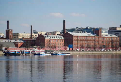 Free Historical red brick industrial buildings reflecting in calm river on a sunny day. Stock Photo