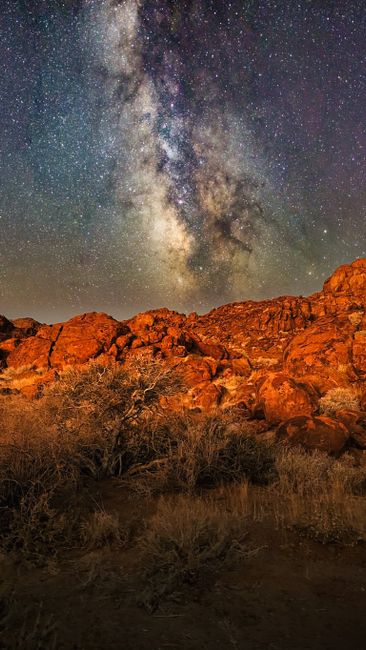 Breathtaking night sky view of the Milky Way above red desert rocks in Namibia.