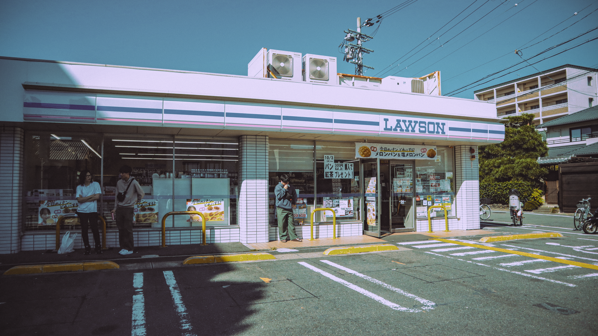 A Kyoto convenience store with people outside on a clear day, capturing local life.