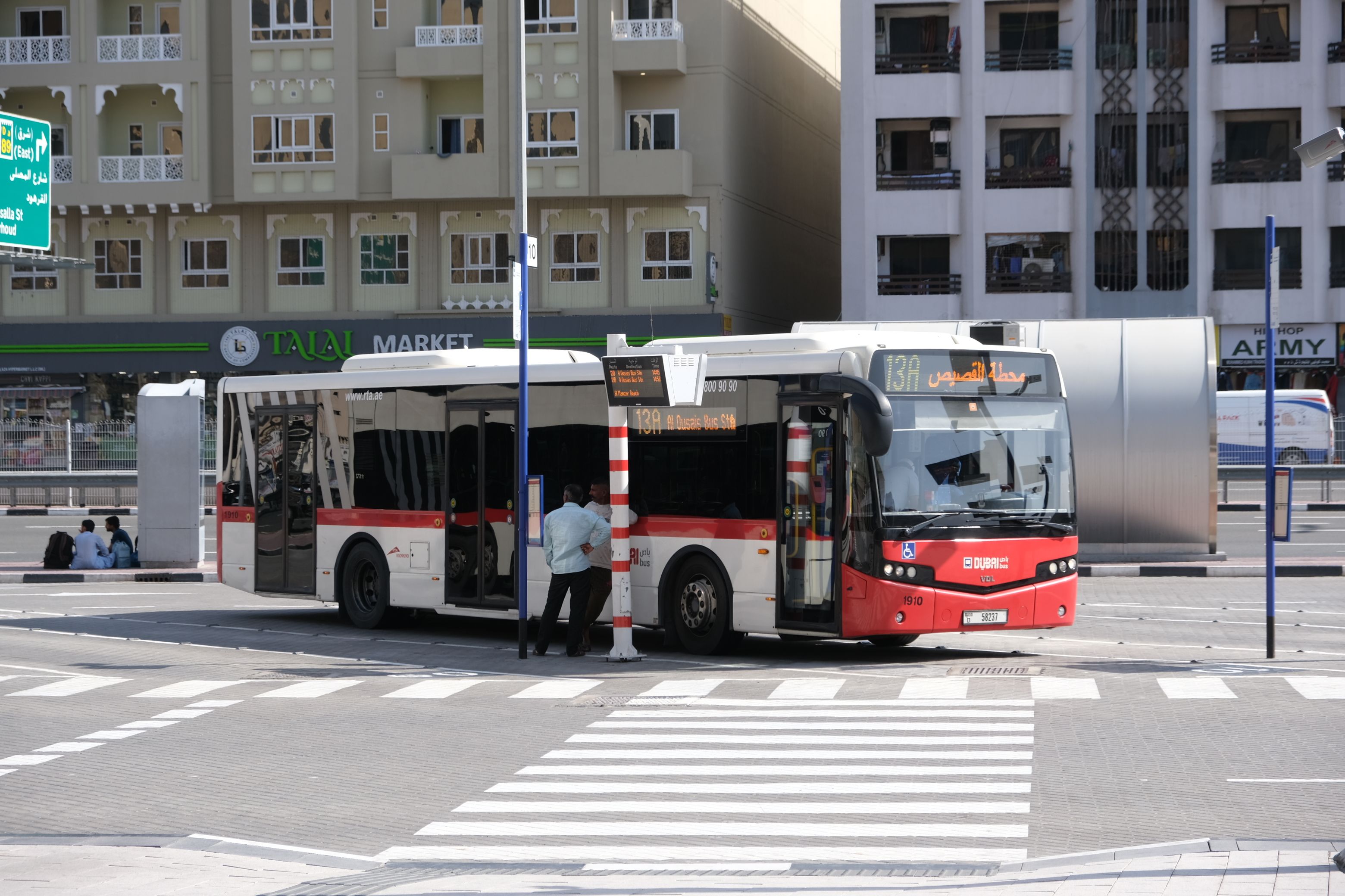Red RTA Dubai Bus driving on a city street with modern architecture