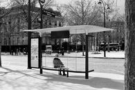 Monochrome image of a bus stop in Paris, showcasing urban life.