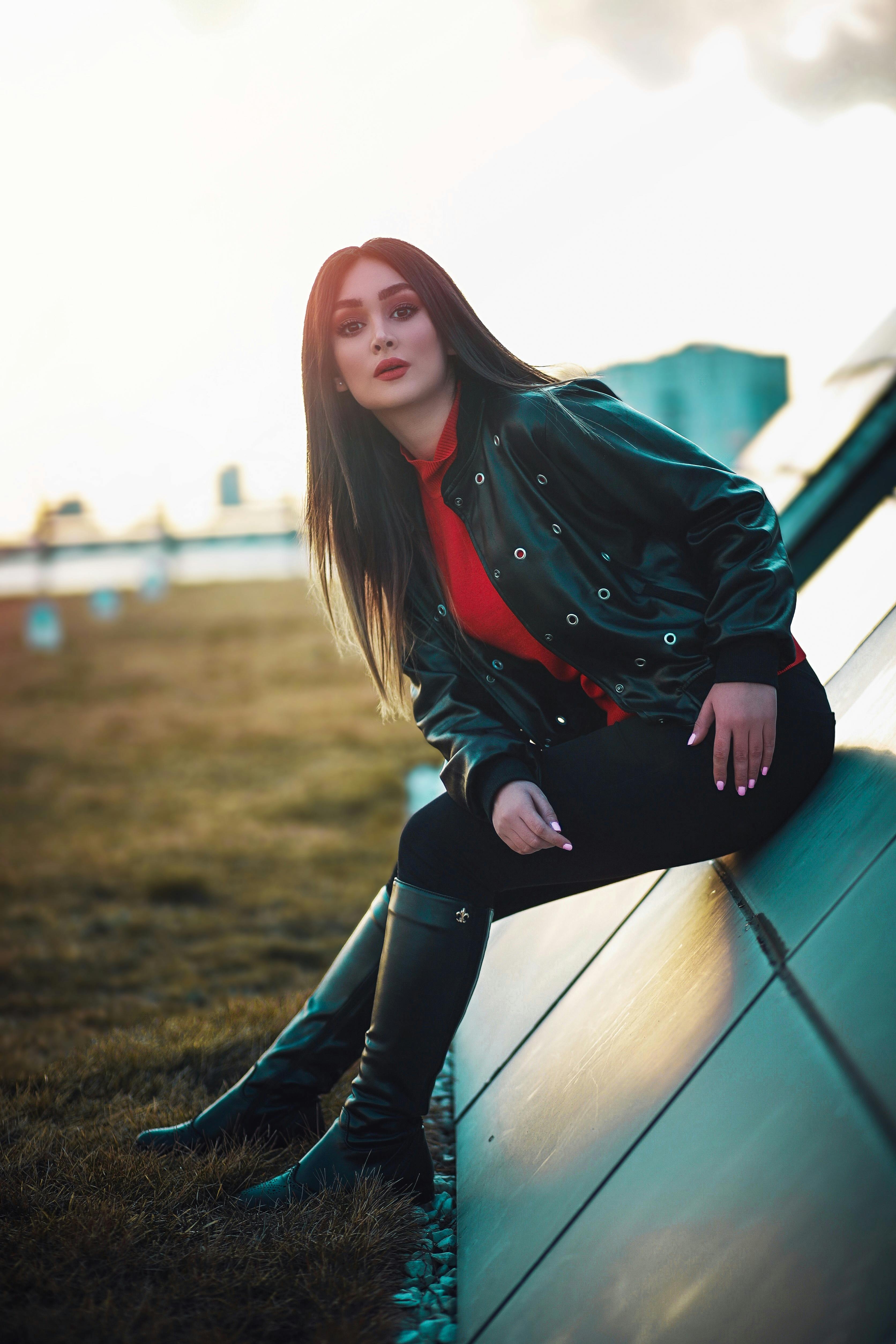 日落时分，一位穿着皮夹克的时尚女士在现代建筑前摆出休闲姿势