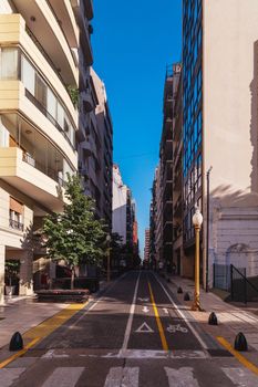 A peaceful city street in Buenos Aires with modern buildings and clear blue skies.