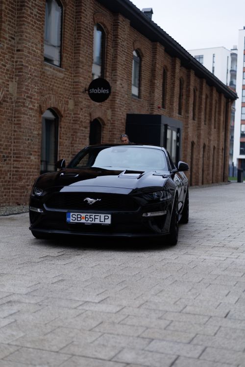 Free Sleek black Mustang car parked on a cobbled street in Cluj-Napoca, Romania. Stock Photo