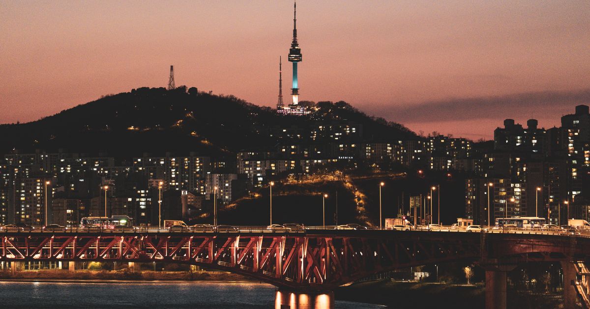 Seoul skyline at night with the illuminated Namsan Tower above the city.