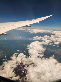 Stunning aerial view of Mount Fuji and clouds from an airplane window.