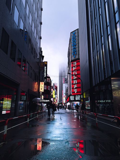 Free Atmospheric view of Shibuya street in Tokyo, Japan with colorful neon lights reflecting on wet pavement. Stock Photo
