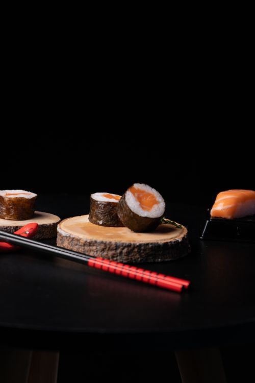 Free Fresh sushi rolls displayed on a natural wood slice with chopsticks in a minimalistic setting. Stock Photo