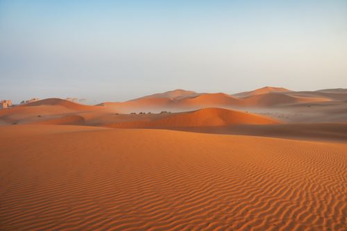 Free Expansive desert landscape with golden sand dunes illuminated by sunrise, showcasing natural patterns and tranquility. Stock Photo