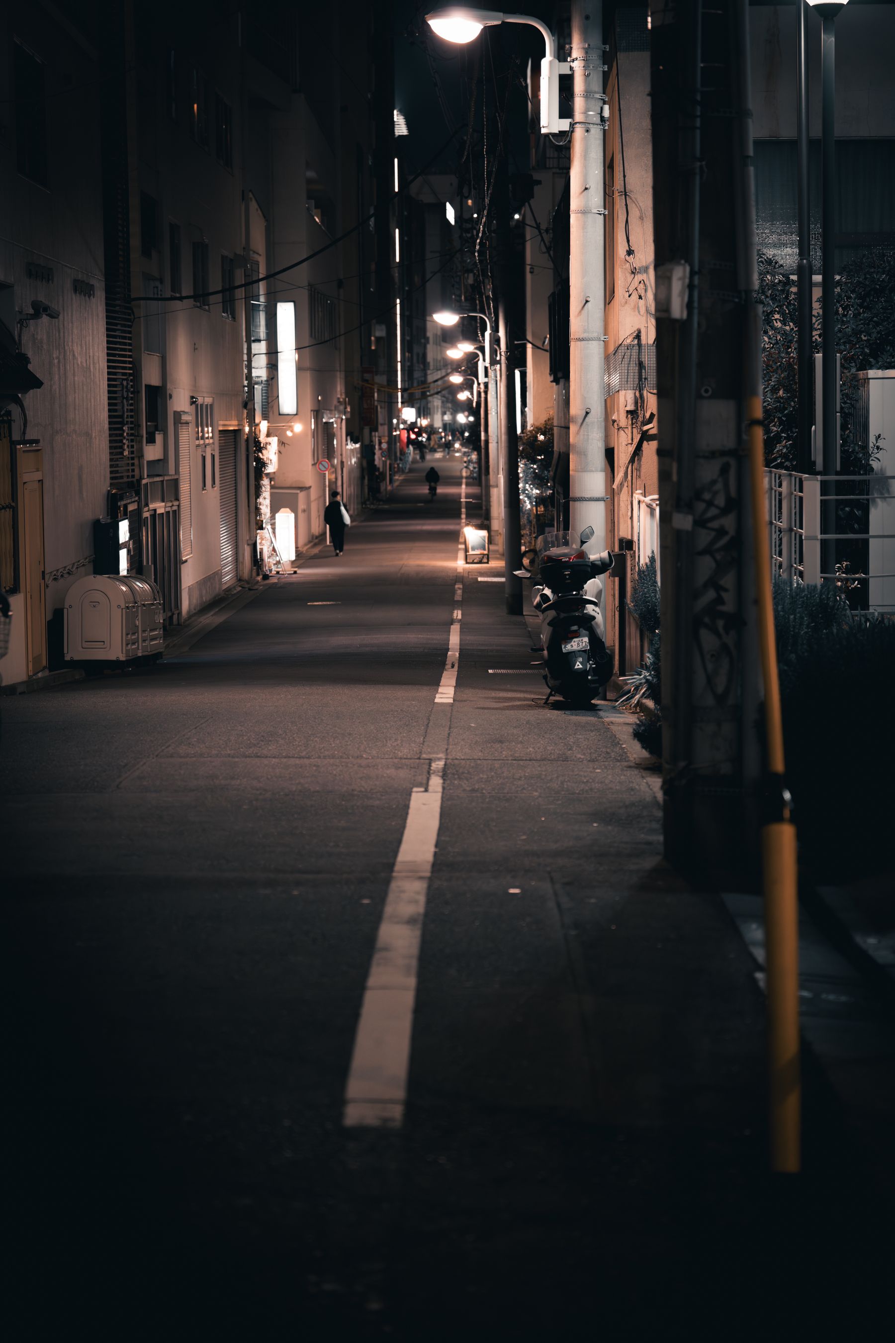 A quiet Tokyo side street at night, wet pavement and vending machine light