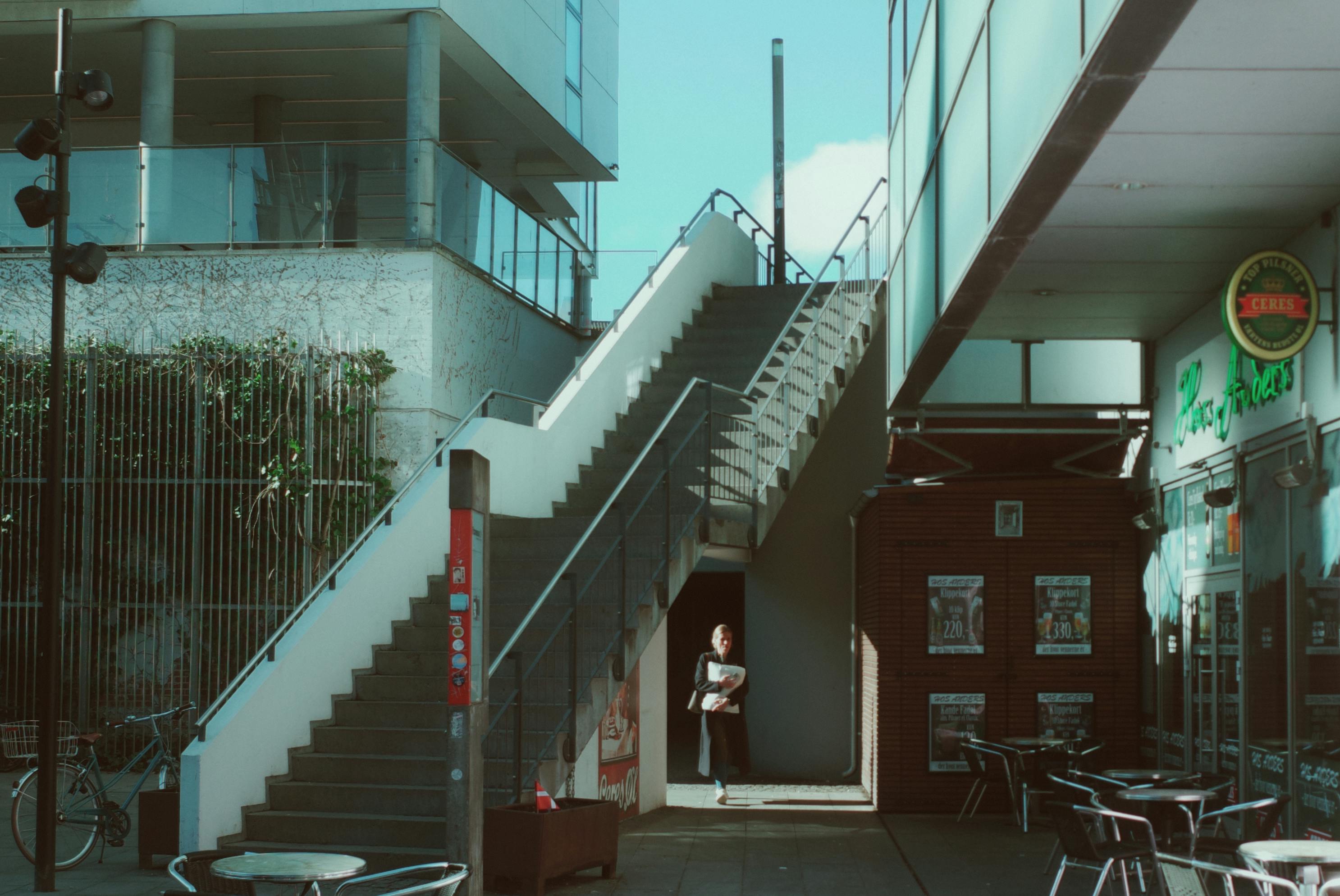Street scene in Aarhus, Denmark featuring a woman by a staircase under a clear sky.