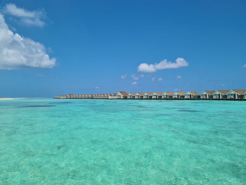 Wooden walkway over turquoise water to overwater bungalows
