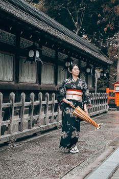 Woman in traditional kimono walking in Kyoto, Japan, near an ancient temple.