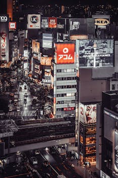Bustling night scene of Shibuya, Tokyo with vibrant lights and busy crosswalks.