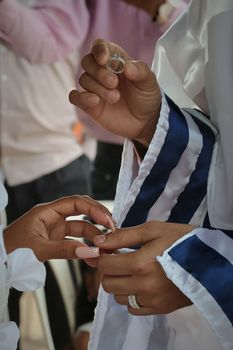 Close-up of hands exchanging rings in a Jewish wedding ceremony.