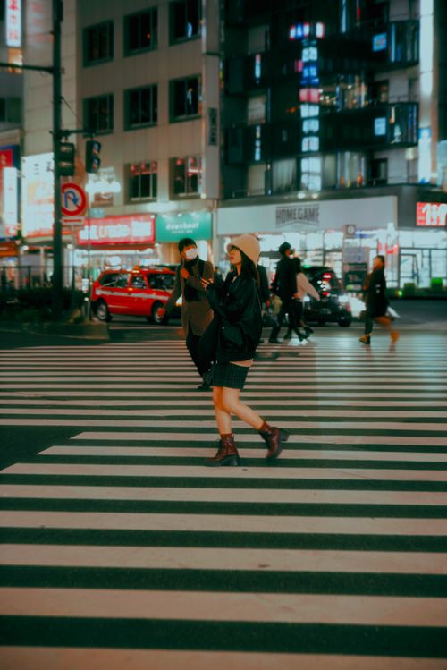 Free People crossing a bustling Tokyo intersection at night, city lights vibrant. Stock Photo
