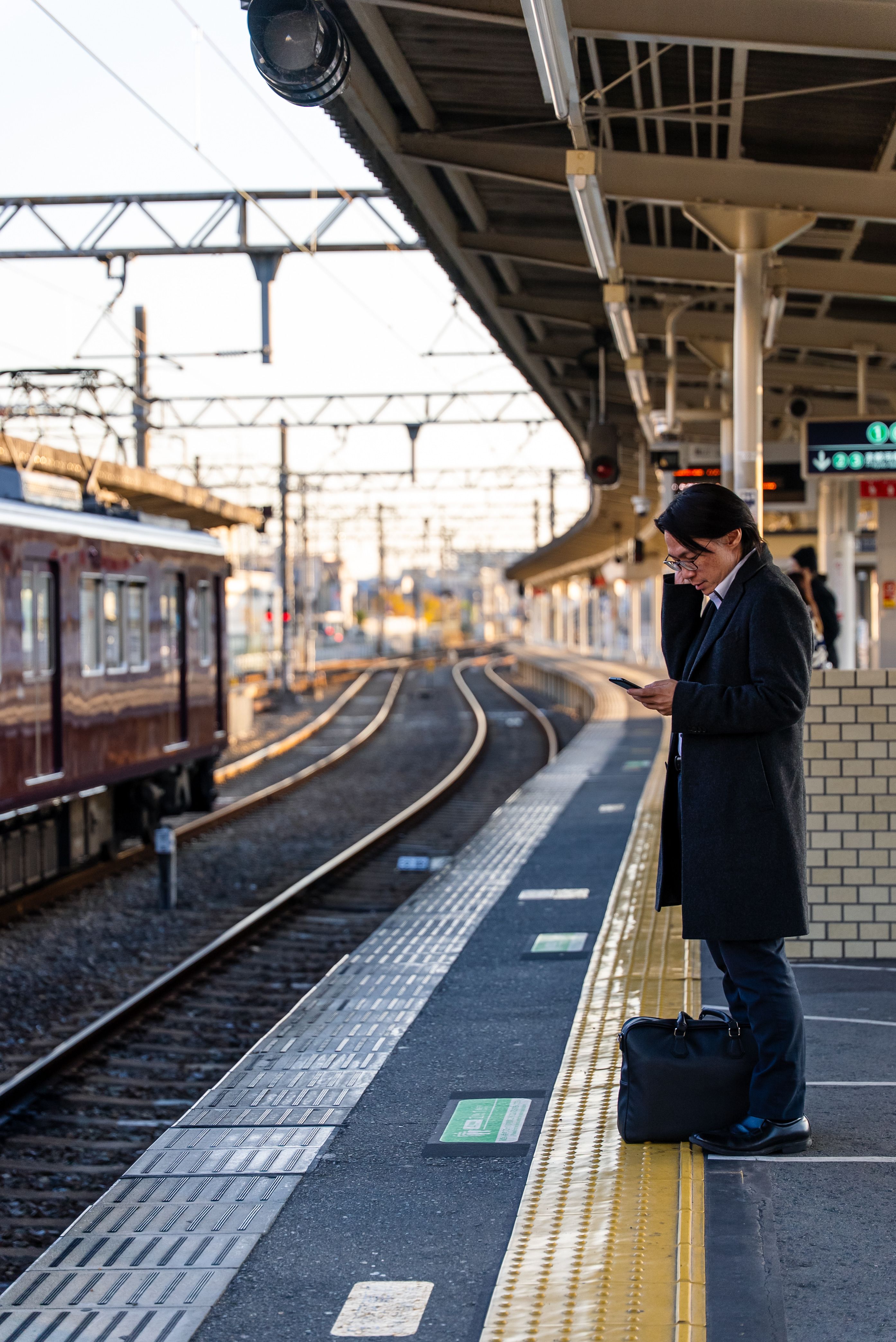 Business professional checking phone at urban train station platform.