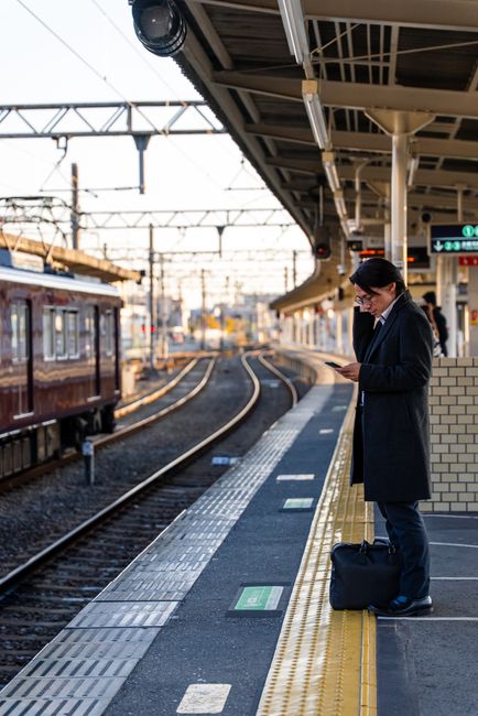 Business professional checking phone at urban train station platform.
