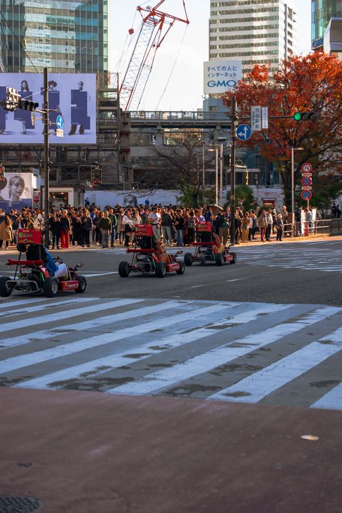 Free Go-karts racing on an urban street with skyscrapers and a crowd of people during fall afternoon. Stock Photo