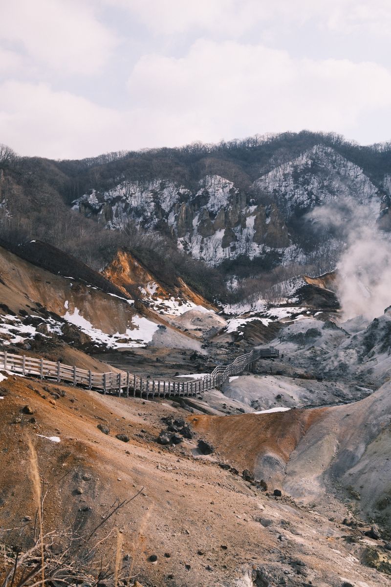 Hokkaido hot spring landscape in winter — onsen steam rising from a mountain valley