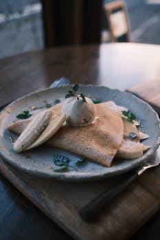 Savor this elegant banana crepe topped with ice cream, beautifully served at a cozy cafe in Nikko, Japan.