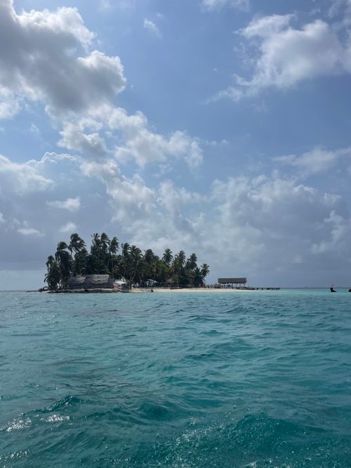 Free A secluded tropical island surrounded by clear blue waters under a sunny sky. Stock Photo