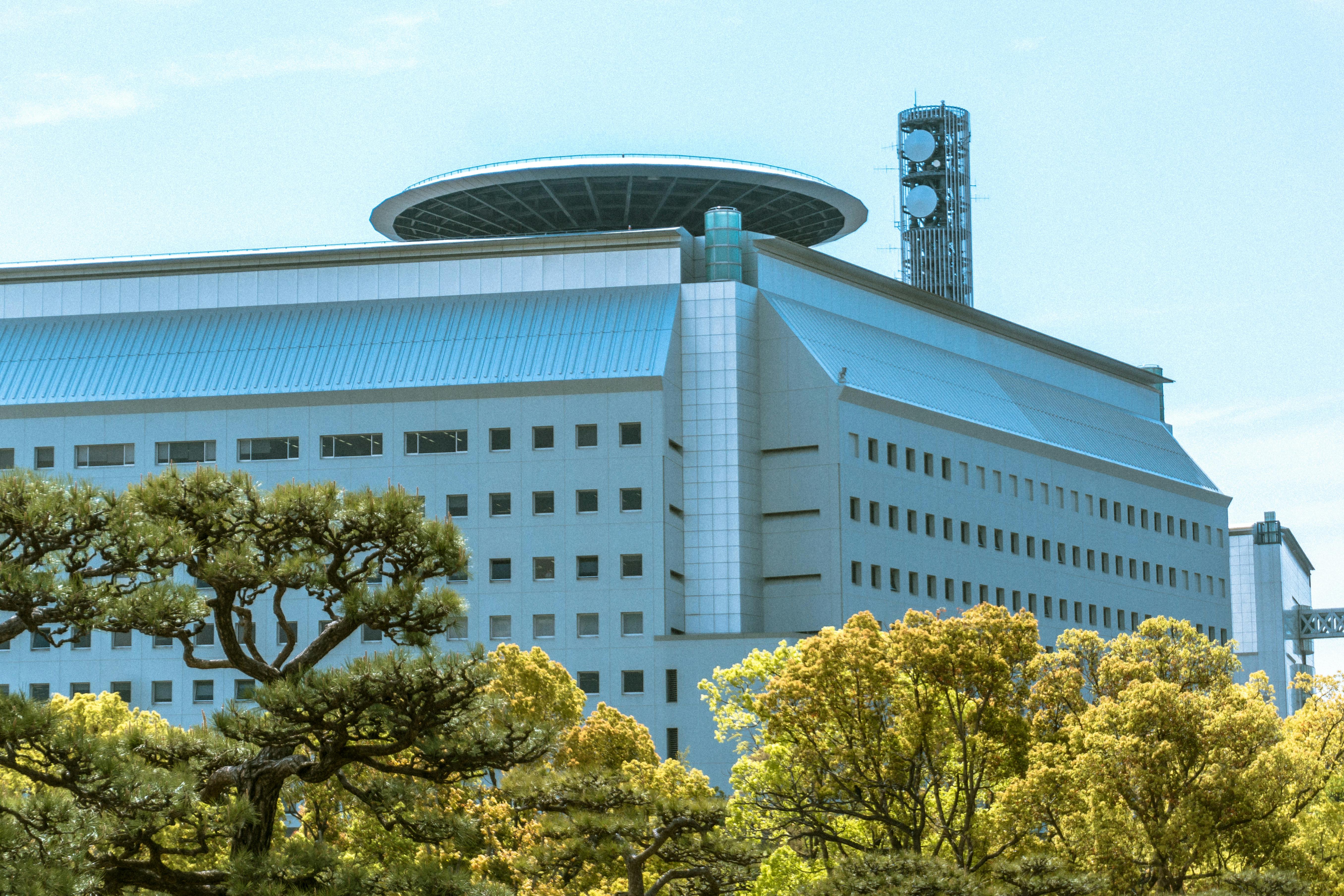 澄み切った青空の下、緑豊かな木々に囲まれた現代的な建築。