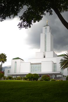 A majestic white temple amidst lush greenery and ominous skies, offering a serene and spiritual ambiance.