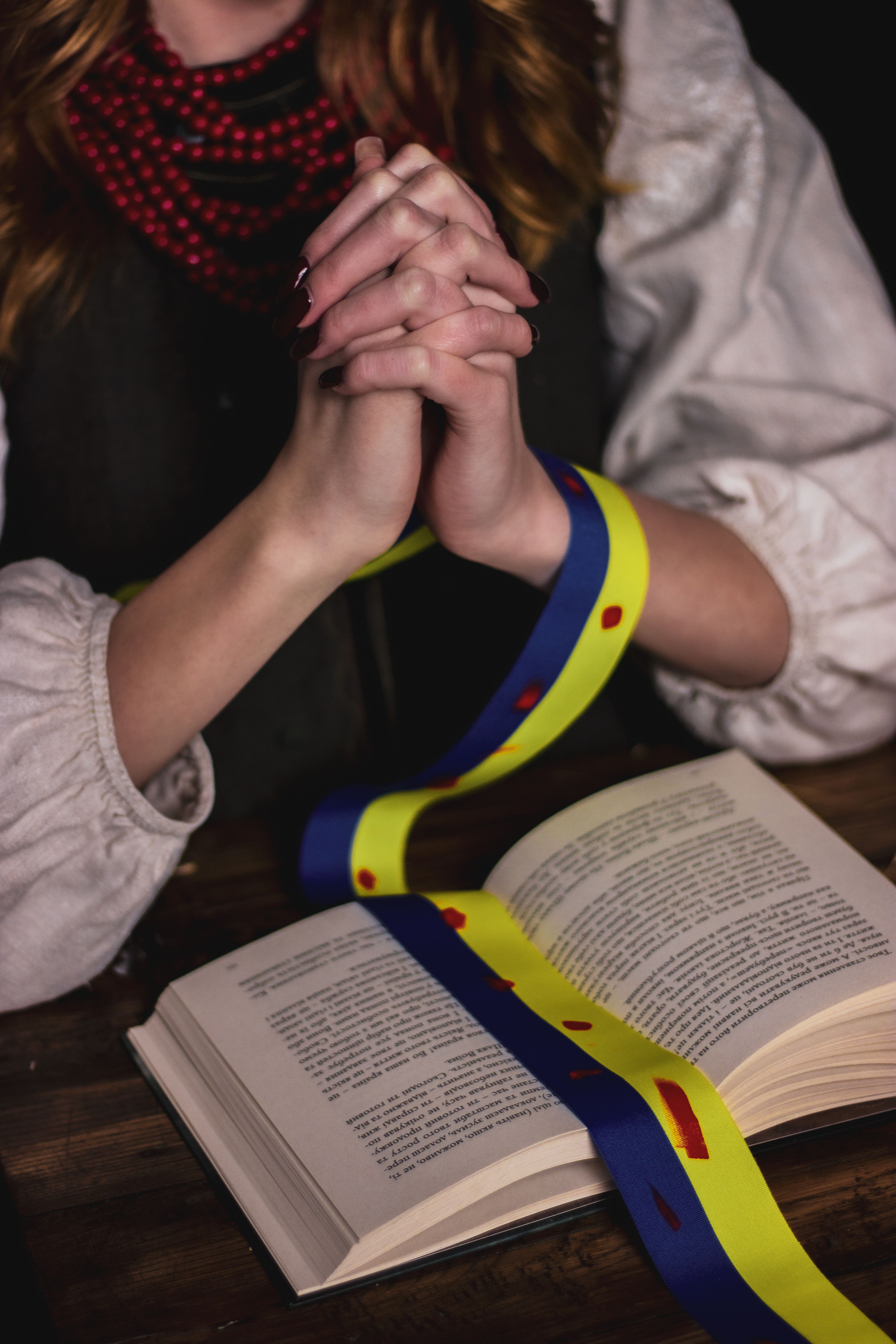 Person Praying with Ribbon and Open Book · Free Stock Photo