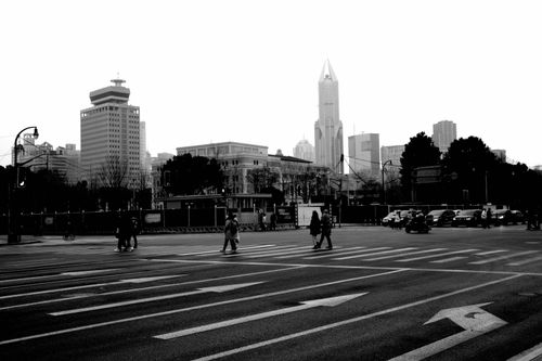 Free Monochrome city scene with pedestrians on crosswalk and towering skyscrapers. Stock Photo