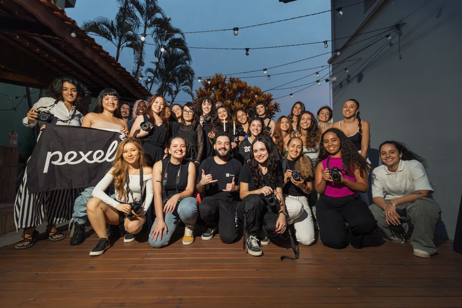 Como Organizar um Encontro Criativo com Amigas: Dicas e Ideias 2 A diverse group of photographers pose outdoors at a photography meetup, showcasing their cameras.