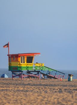 Vibrant rainbow lifeguard tower on the sandy shores of Venice Beach, Los Angeles.