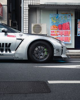 Side profile of Nissan GT-R parked on a Tokyo street, showcasing automotive design and urban vibe.