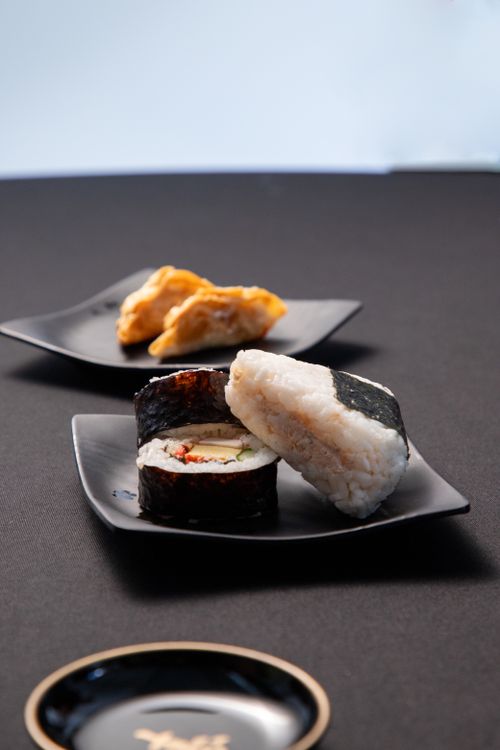 Free Artistic display of sushi and dumplings on black plates, perfect for culinary themes. Stock Photo