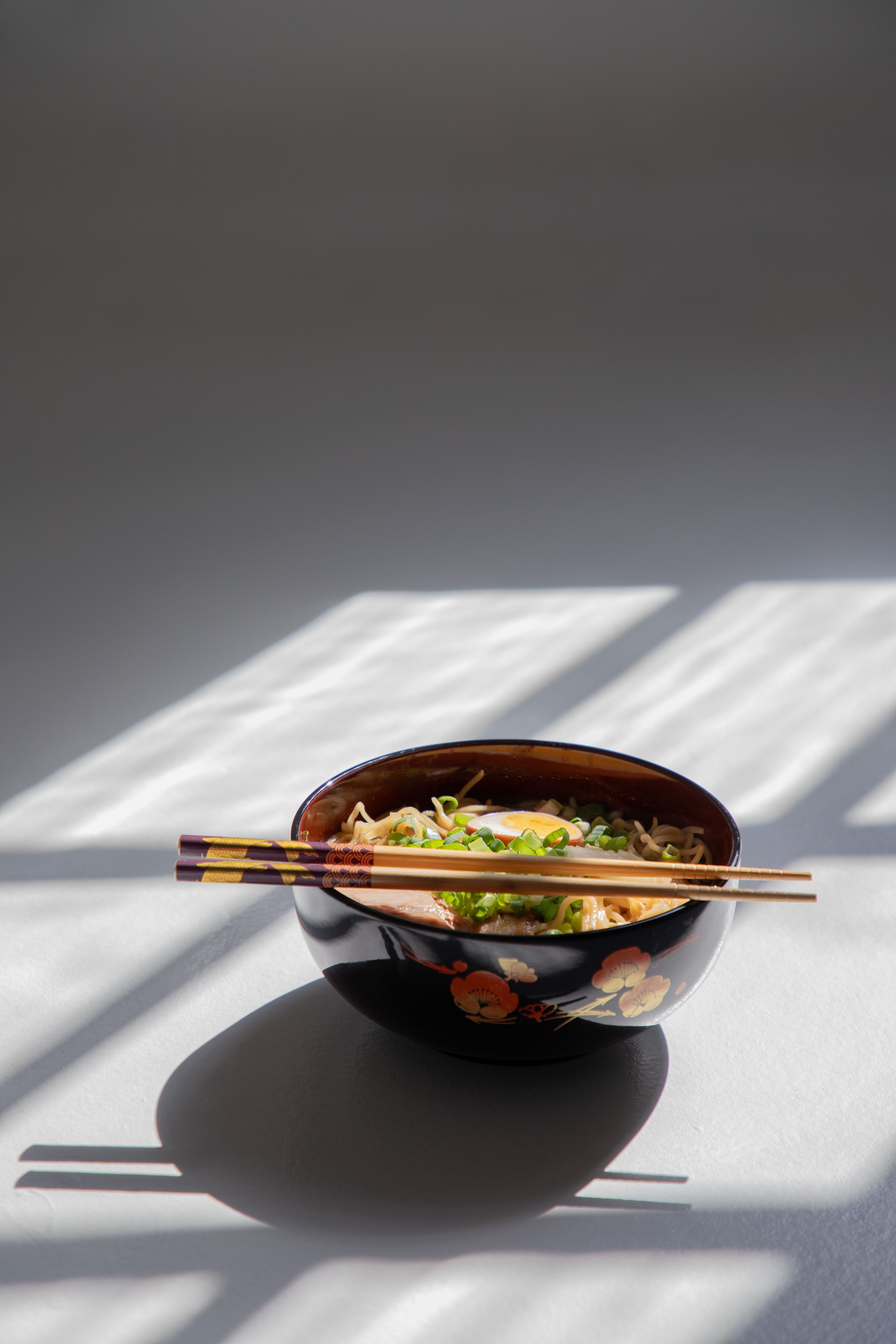 A beautiful bowl of Asian noodles with chopsticks in natural light, perfect for culinary themes.