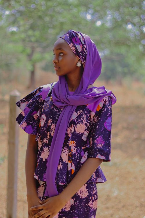 Free Young woman in a vibrant purple outfit poses elegantly outdoors, showcasing cultural fashion. Stock Photo