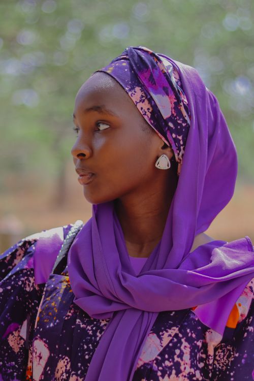 Free A serene portrait of a woman wearing a vibrant purple hijab in an outdoor setting. Stock Photo