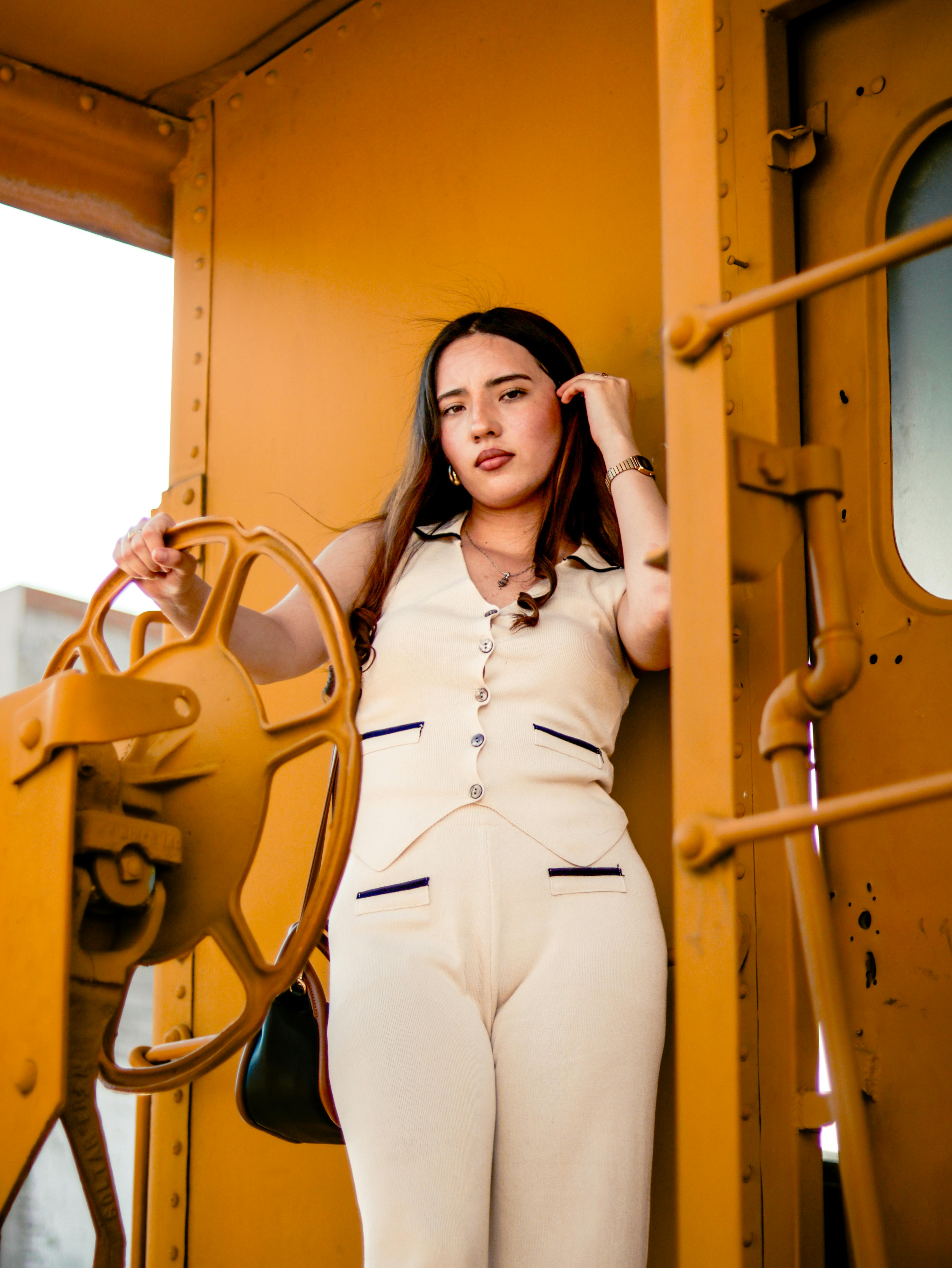 Free Young woman posing inside a vintage train cabin, wearing a beige outfit. Stock Photo