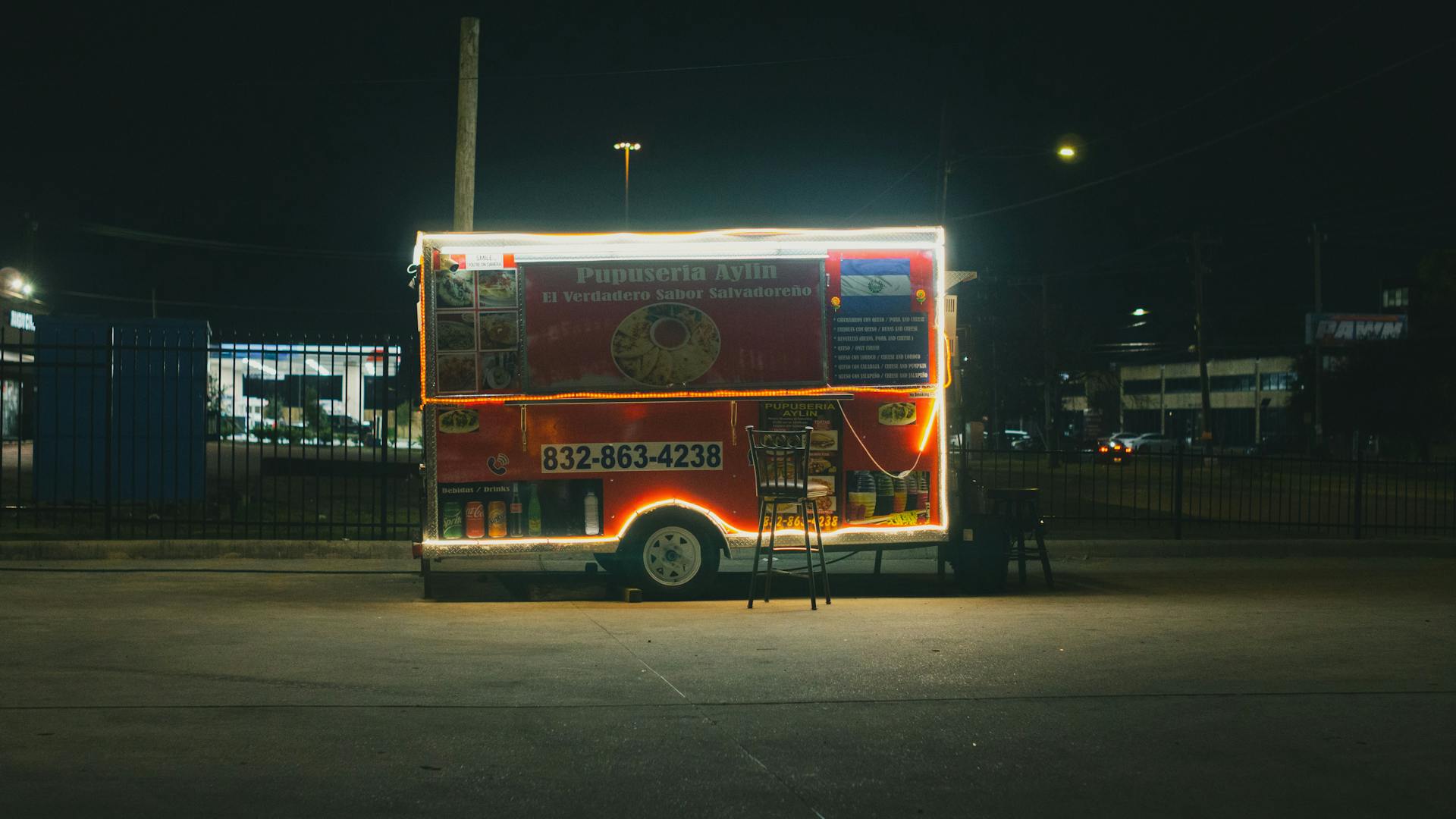 Illuminated Salvadoran food truck stands colorful against the night in Houston, Texas.