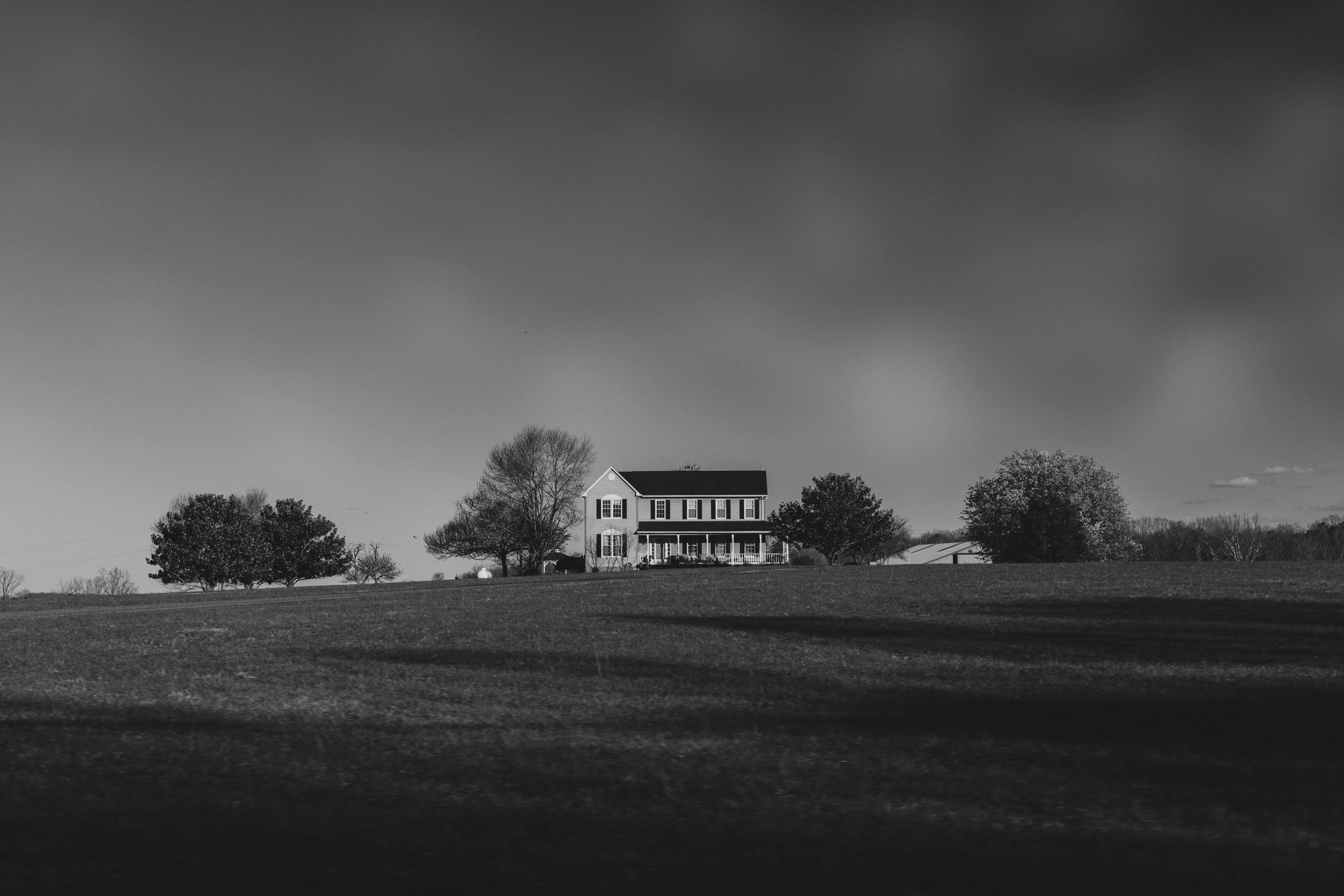 Black and white photo of a solitary house amidst a vast open field in Charlottesville, Virginia.