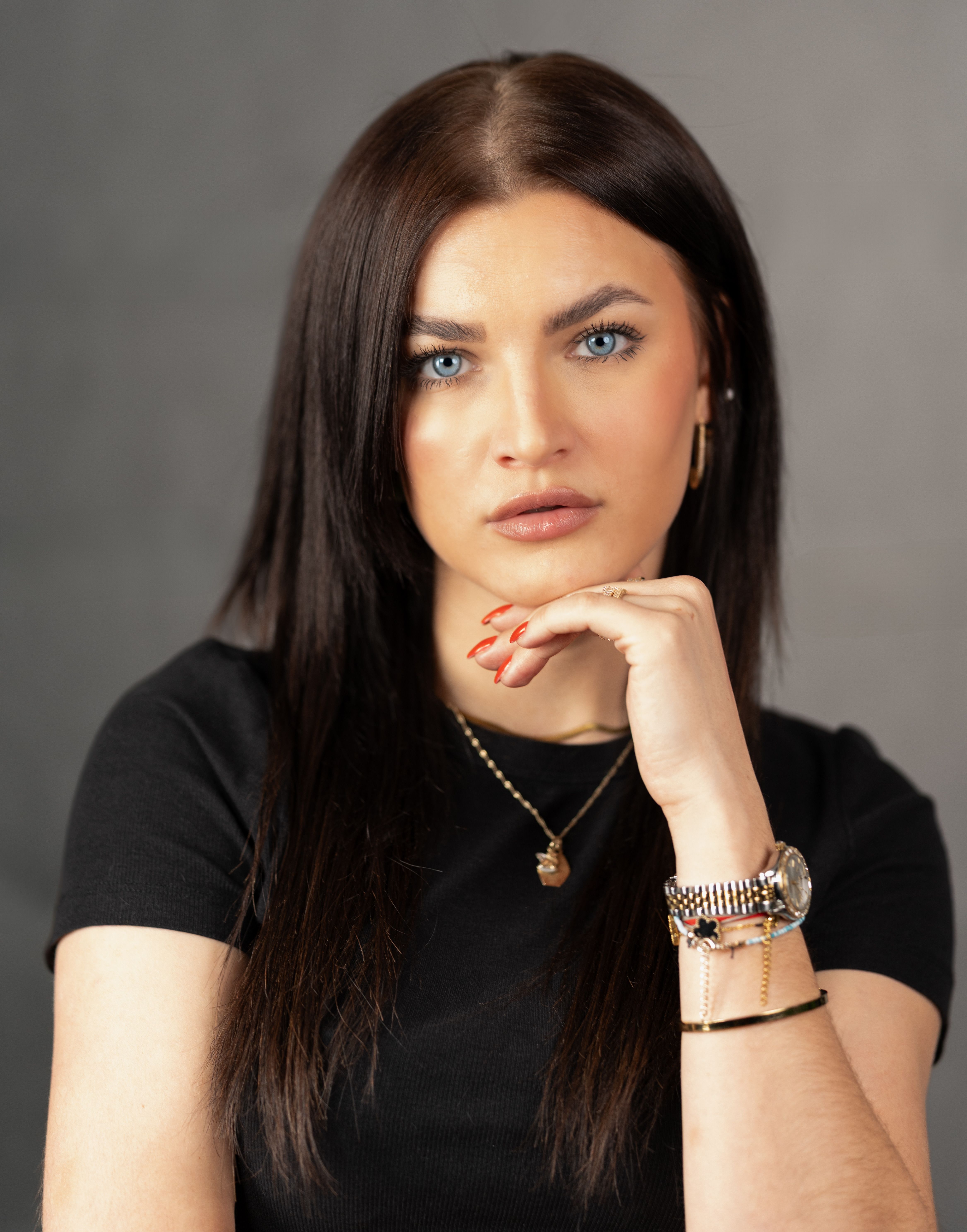Elegant portrait of a confident woman with striking blue eyes and dark hair in a studio setting.