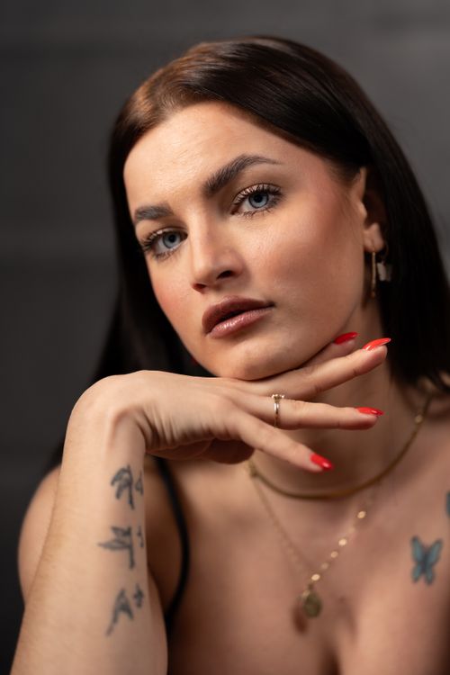 Free Close-up portrait of a woman with tattoos, elegant makeup, and jewelry on a dark background. Stock Photo