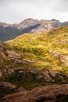 A serene view of rugged mountains under natural light with a grassy foreground.