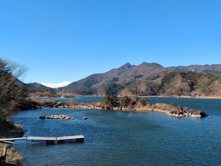 Serene view of Lake Saiko with surrounding mountains in Fujikawaguchiko, Japan.