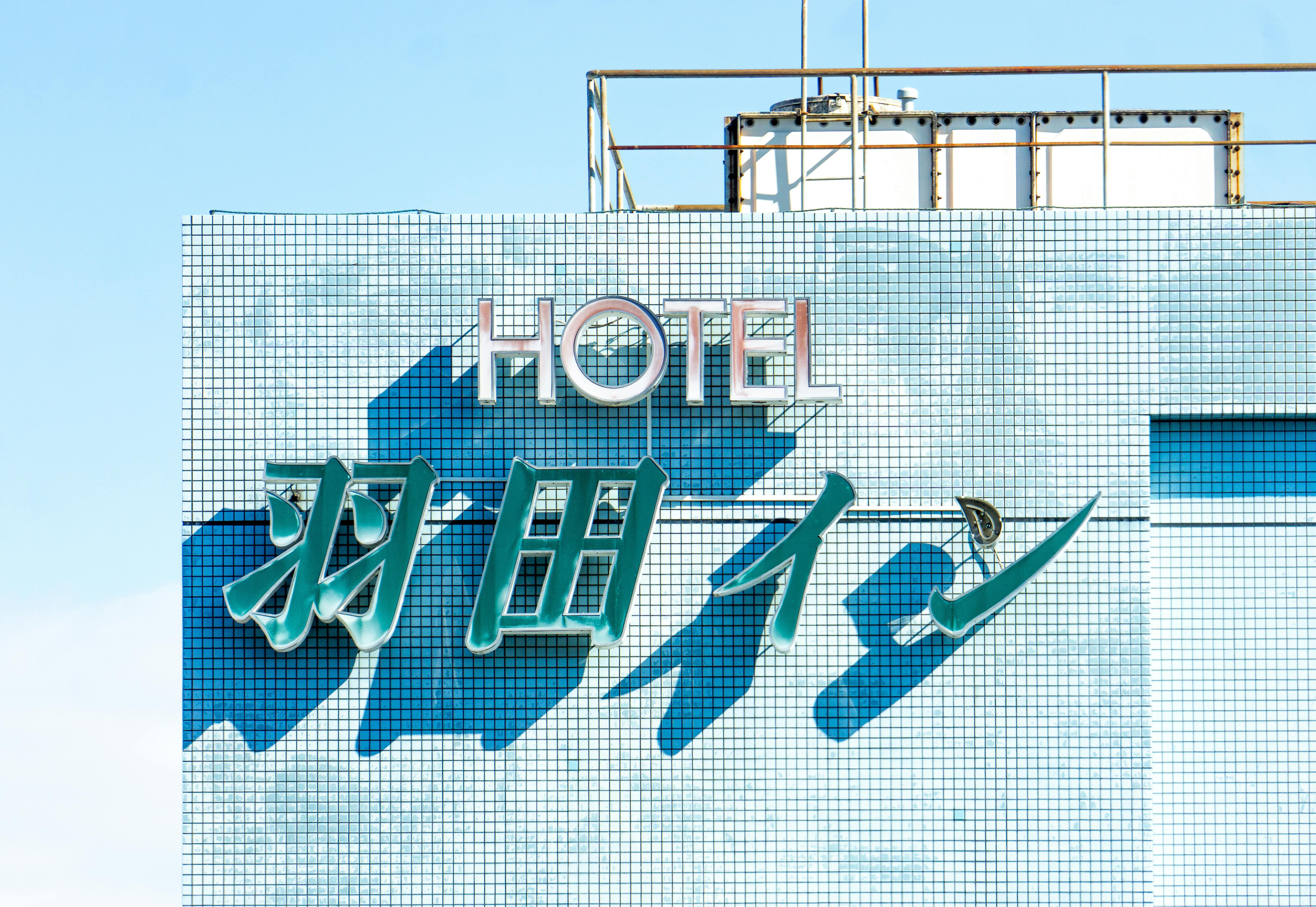 Brightly lit hotel sign with blue tiles under a clear sky, showcasing modern architecture.