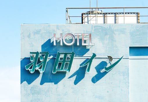 Brightly lit hotel sign with blue tiles under a clear sky, showcasing modern architecture.